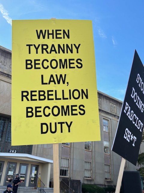 A sign on a yellow background saying, "WHEN TYRANNY BECOMES LAW, REBELLION BECOMES DUTY"